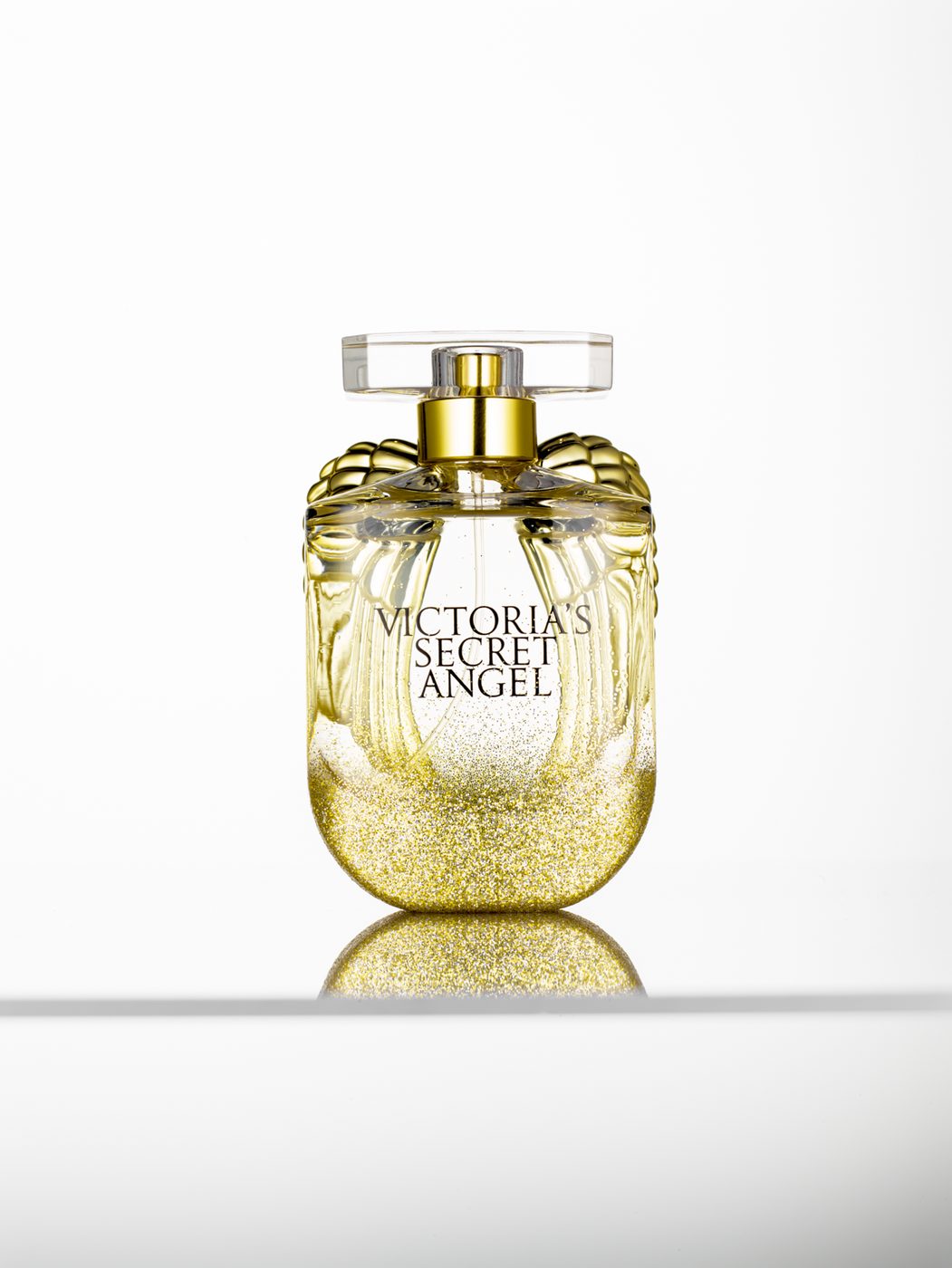 Gold perfume bottle photographed on a clean white surface with a controlled reflection